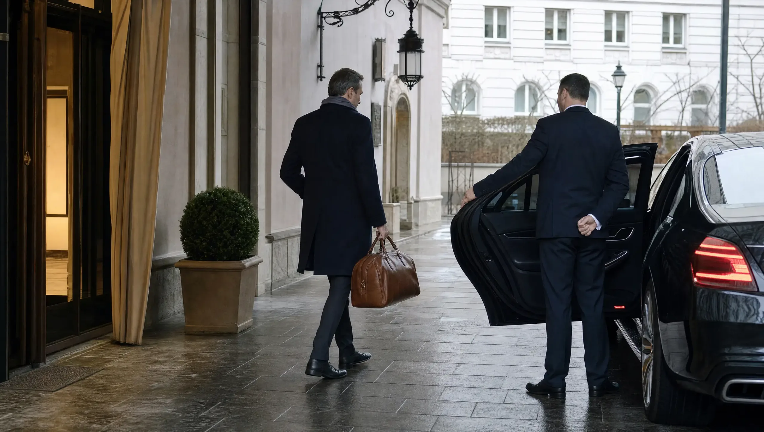 Chauffeur öffnet die Fondtür vor der Vorfahrt eines Hotels